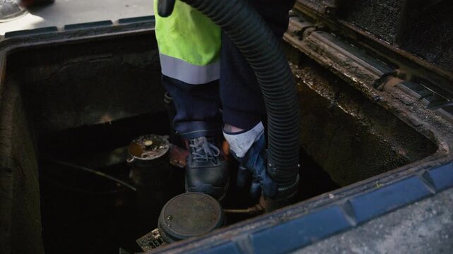 Tanker truck worker connects fuel hose to tank at gas station