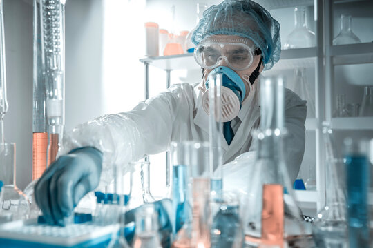 Scientist with chemical glassware in a laboratory. Concept of laboratory safety, hazardous substances, contamination control, scientific protocols and professional research environment.