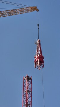Slow motion shot of the 450-ton crane's telescopic boom precisely aligning the heavy steel tower top with the mast.