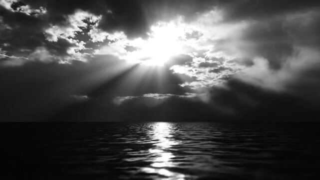 Dramatic seascape with sun shining through stormy clouds over calm ocean waters in monochrome