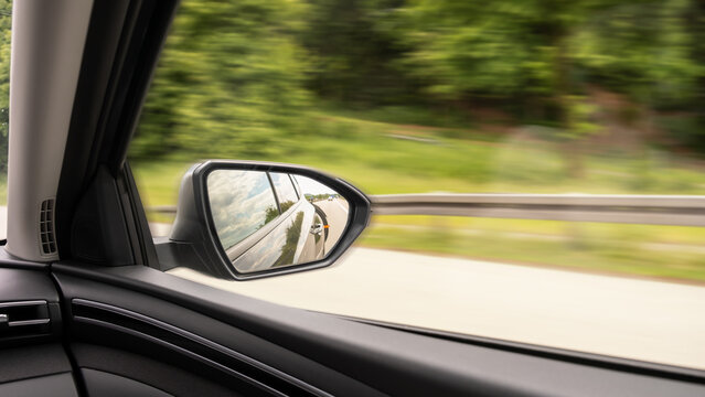 View from moving car with side mirror reflection on highway, motion blur traffic and transportation concept, safety and traffic rules, car insurance, copy-space.