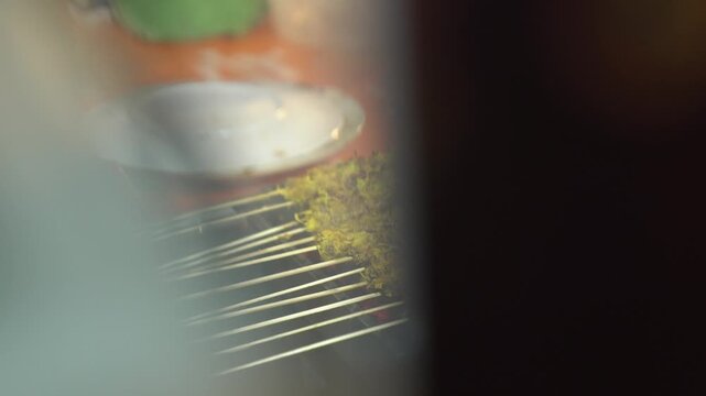 Sate klatak grilling over charcoal, close-up of traditional Yogyakarta goat satay in a smoky Indonesian street food stall.