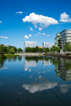 A cloud becomes reflection in the water at La Confluence, Lyon France, as river architecture, skyline and urban space open under blue sky