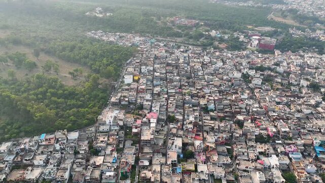 Drone orbit highlighting deforestation and stark boundary between concrete buildings and woods.