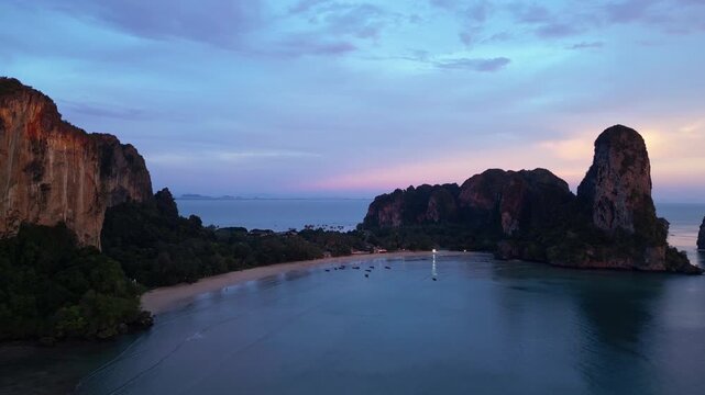 Railay beach, Thailand: Aerial drone footage of the dramatic Railay, or Raliey beach in Krabi in Thailand by the Andaman sea. Shot with a backward motion at sunset during the rainy season.