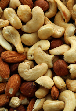 Almond and cashew nuts in big pile on table close up. Large amount of brown nuts