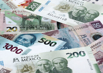 Fototapeta premium Mexican peso money banknotes pile on table. Mexico bills of MXN currency close up