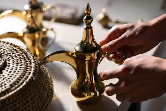 Close up of hands holding traditional golden Arabian coffee dallah with woven basket in sunlit luxury interior