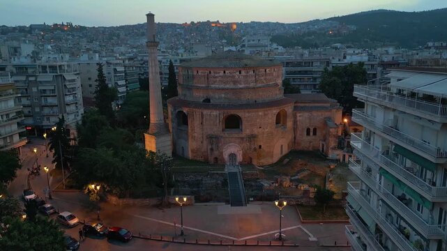Aerial evening view of the illuminated historic Rotunda monument and its minaret in Thessaloniki, Greece, during twilight.