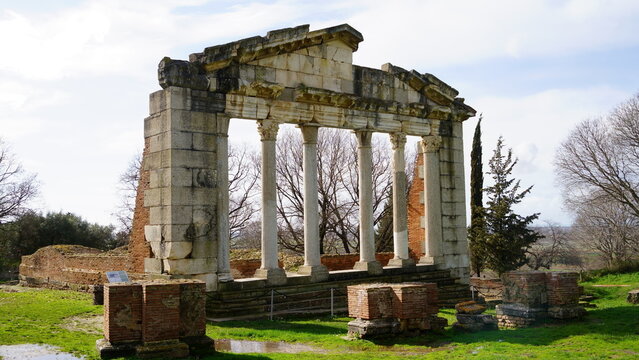 A stationary medium shot of the reconstructed Corinthian facade of the Bouleuterion at Apollonia Archaeological Park, showcasing ancient Roman masonry and columns in a green landscape