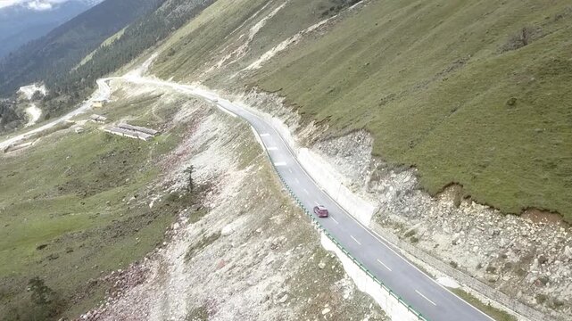 Red car driving on high mountain road.