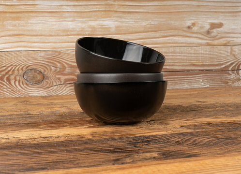 Empty bowl on table, black plate on wooden table, dark porcelain dish mockup, rustical kitchen