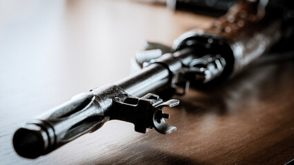 Metal gun rests on wooden surface © I