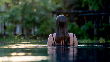 Woman stands in calm pool, back to camera © I
