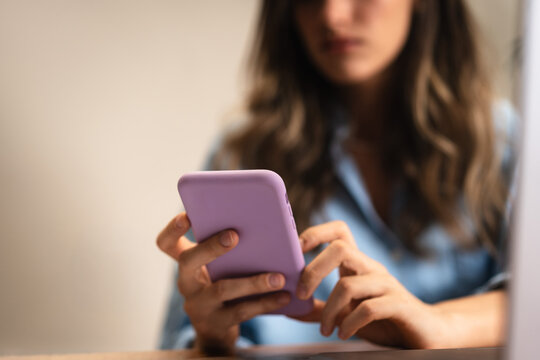 Close up of female hands using smartphone with purple case in casual indoor setting. Woman using smartphone with focus on hands and purple phone case in an indoor setting.
