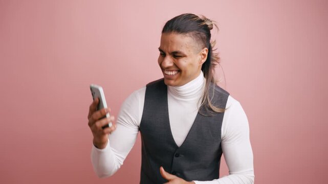 Handsome latino man feeling happy and excited while looking at his smartphone. He smiles and makes a winning gesture with his fist