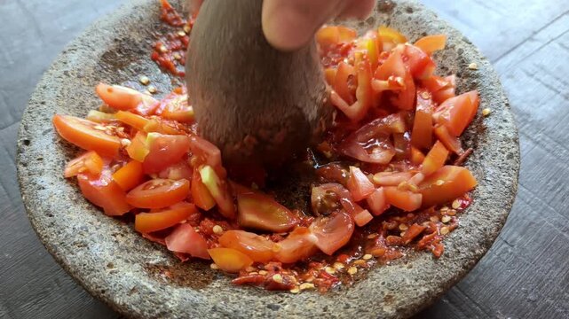 Hand Grinding Fresh Tomato Chili Sambal in Traditional Stone Mortar and Pestle (Ulekan)