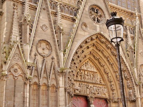 Close-up of the Saint Stephen Portal on the south facade of Notre-Dame de Paris. The image features intricate Gothic stone carvings, a detailed tympanum depicting biblical scenes, and a traditional Pa