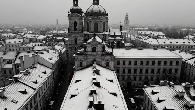 Aerial view of a snow-covered church and cityscape in black and white during winter