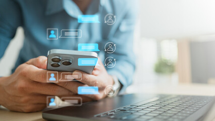 Obraz premium Professional using smartphone beside laptop with live chat icons, representing customer support, AI assistant and instant online communication for modern business service.