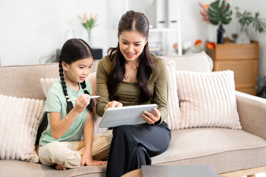 Asian Mother and Daughter Using Digital Tablet for E-learning at Home