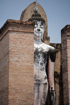 Golden Kinnari statue (mythical half-human, half-bird) in front of a Thai style building in Thailand.