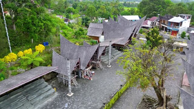 Aerial drone footage of traditional Batak houses surrounded by tropical forest in Samosir Indonesia