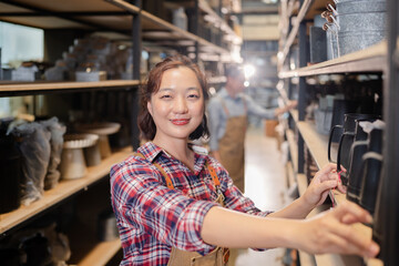 Fototapeta premium portrait of asian woman staff in plaid shirt check merchandise inventory count in store rack, warehouse worker working in distribution shipping logistic center support fulfillment supply chain