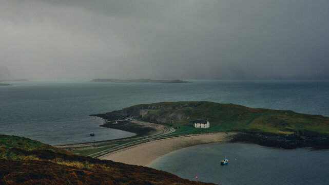 cottage in scenic headland by fishing boats in stormy weather