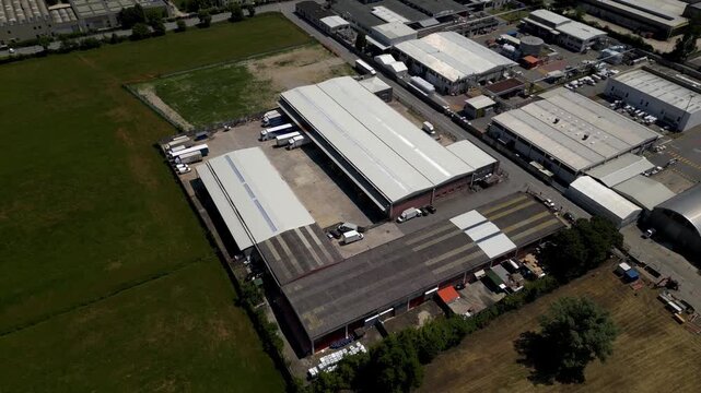 Aerial View of Industrial Park: An expansive aerial photograph reveals a bustling industrial park with large warehouses and manufacturing facilities, surrounded by green fields and a clear sky.
