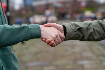 Fototapeta na wymiar People shake hands in a city setting during a meeting on a cloudy day in the afternoon