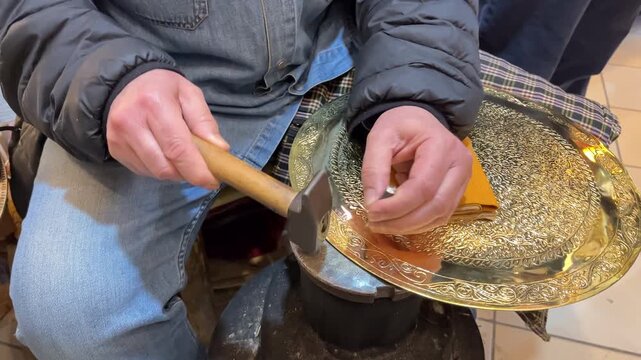 Craftsman engraving patterns on the tray. Manual copper minting, the old art of etching on utensils