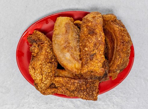 Crispy deep fried bagnet pork belly served on red plate