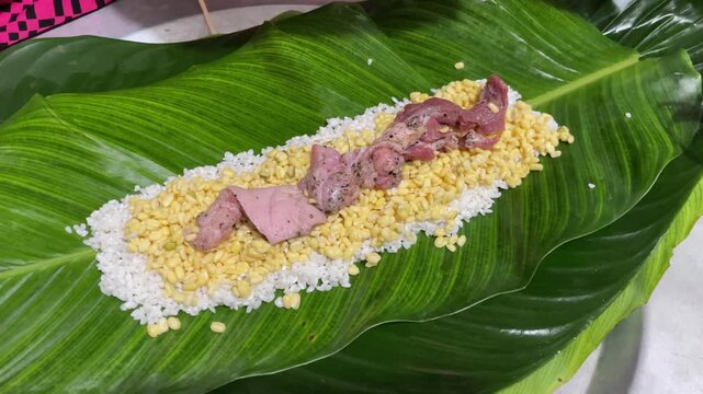 Woman&rsquo;s hands spreading sticky rice, mung beans, and pork on banana leaf to wrap banh tet in Vietnam for Tet food preparation and cultural cuisine themes.
