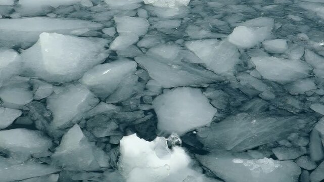 Close-up aerial view of fractured ice floes floating on dark water
