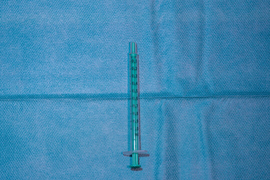 Single 1ml Medical Syringe with Green Plunger on Blue Sterile Drape - Precision Injection and Vaccination Equipment