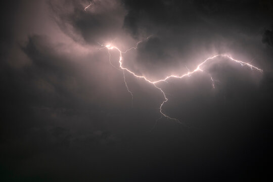 Dramatic lightning striking through dark storm clouds at night