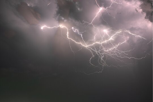 Dramatic lightning strikes illuminating dark stormy clouds at night