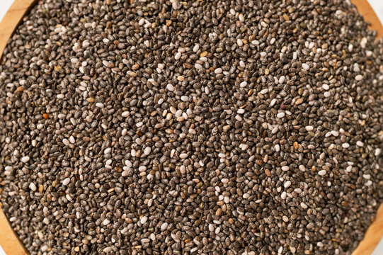 Close-up of dry chia seeds in wooden bowl, top view. Food background, healthy seeds for breakfast, snacks, chia pudding. Superfood, texture of Salvia hispanica seeds
