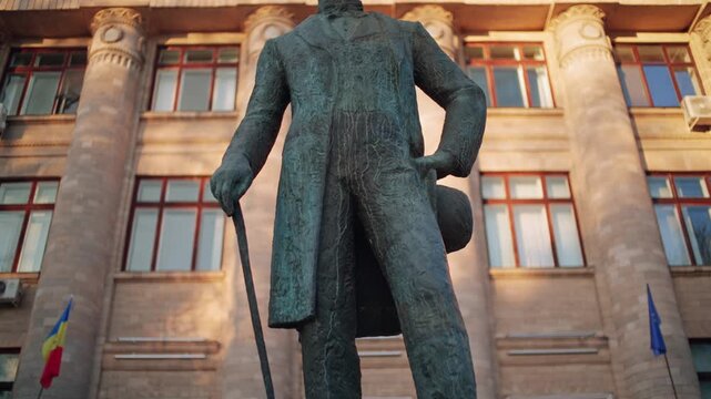 Bronze statue of Vasile Alecsandri in front of the classic building on a sunny day in Moldova capital.