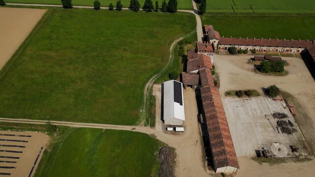 Aerial View of Agricultural Farm: An expansive aerial perspective showcases a working farm with arable fields, rustic buildings, and modern solar panels.