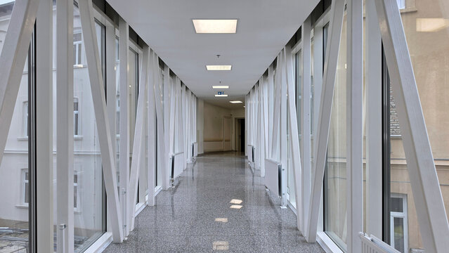 Modern glass skywalk bridge with white steel truss structure and polished granite floor