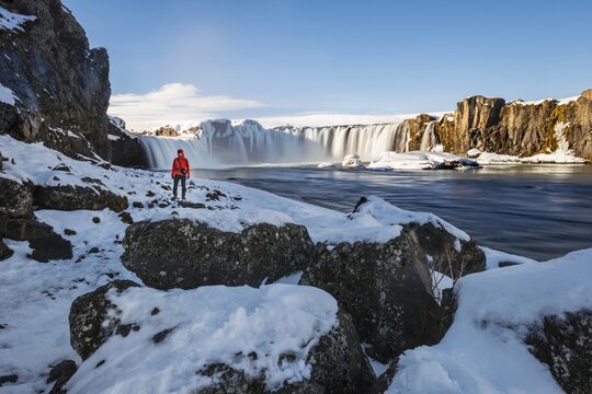 Man in front of waterfall G&oacute;&eth;afoss, Godafoss in winter with snow and ice, Skj&aacute;lfandaflj&oacute;t river, Nor&eth;urland vestra, Northern Iceland, Iceland