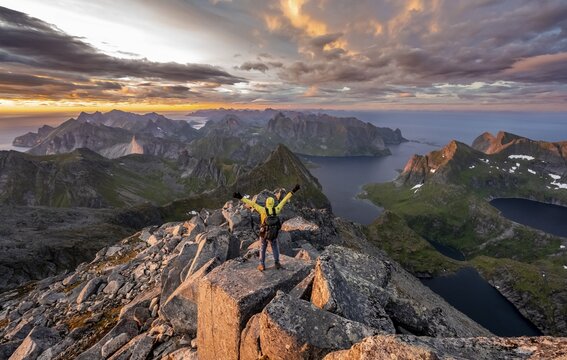 View over mountain top and sea, dramatic sunset, mountaineers at Hermannsdalstinden peak, with lakes Litlforsvatnet and Tennesvatnet and fjord Forsfjorden, Moskenes&ouml;y, Lofoten, Nordland, Norway