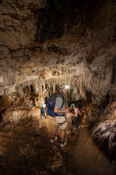Young man with helmet and headlamp, tourist between stalactites and stalagmites in a stalactite cave, Terciopelo Cave, Barra Honda National Park, Costa Rica