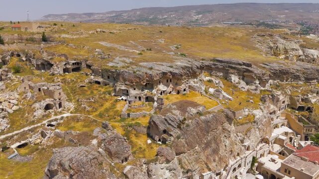 Urgup, Nevsehir, Turkey. Abandoned rock-cut dwellings carved into volcanic tuff formations, aerial drone view over the arid Cappadocia plateau. Aerial View