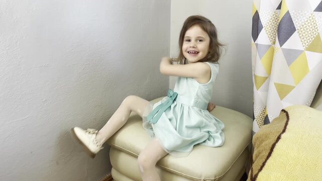 Happy child sitting on a pouf with empty wall background for copy space
