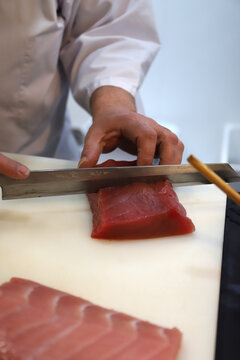 chef profesional cortando trozos de at&uacute;n rojo para elaboraci&oacute;n de sushi