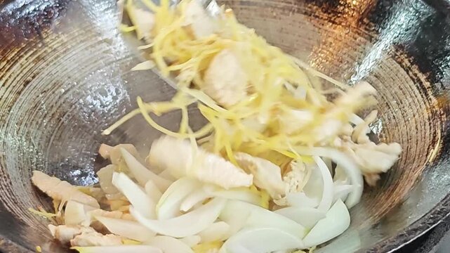 Stir-frying sliced chicken with ginger and onions.