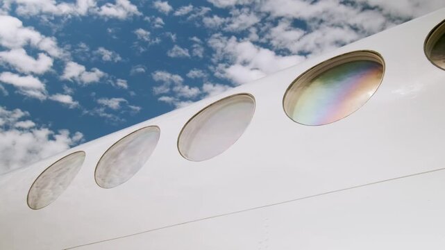 Close-up of airplane passenger windows on white fuselage reflecting sunlight, illustrating modern aviation transport, aircraft design and travel industry concept.